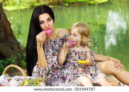 mother and daughter playing in the same clothes on nature on a background of the river