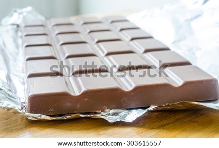 Milk chocolate bar in open foil wrapping ready for eating.