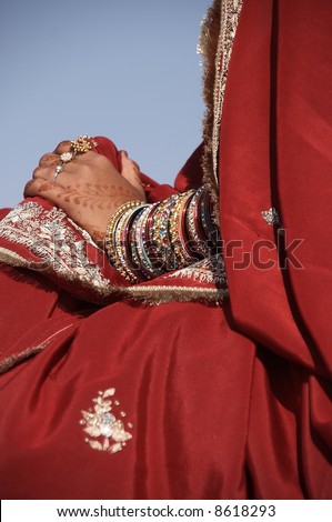 Indian lady in ornate red sari. Hands adorned with bangles and jewelery. Desert Festival Jaisalmer Rajasthan India.