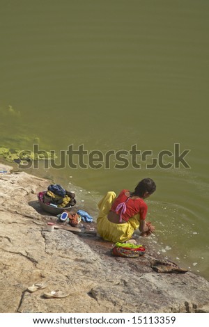 CHITTAUGARH, INDIA - NOVEMBER 14: Unidentified Indian lady squatting on a rock washing clothes in a lake. November 14, 2007 in Chittaugarh, Rajasthan, India.