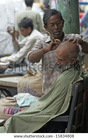 DELHI, INDIA - JULY 17: Unidentified man having his head shaved by a street barber in Old Delhi. July 17, 2008 in Delhi, India.