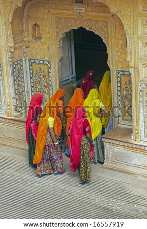 Indian women in bright orange saris in the courtyard of a Rajput palace. Tiger Fort, Jaipur, Rajasthan, India