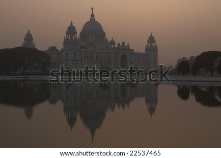 Victoria Memorial in Kolkata, India. Ornate white marble building reflected in an ornamental lake at dusk.