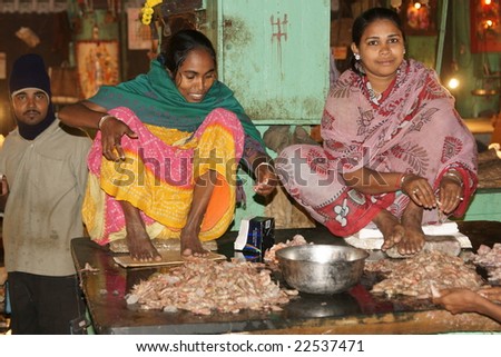 KOLKATA, INDIA - DECEMBER 18: Unknown women in brightly colored sari\'s shelling prawns in the fish market on December 18, 2008 in Kolkata, West Bengal, India