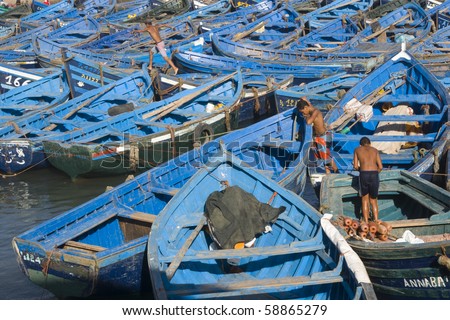 ESSAOUIRA, MOROCCO - AUGUST 27: Young men at work on a fleet of wooden fishing boats on August 27, 2009 in the fishing village of Essaouira, Morocco.