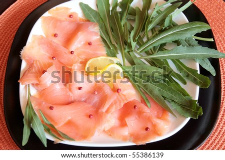 A dish of smoked salmon with red pepper and rocket