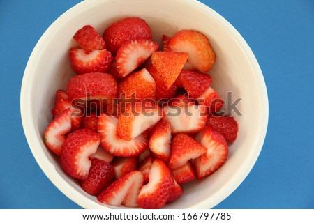 Strawberry Bowl Fresh juicy strawberries sliced in a round white bowl.  The strawberry bowl, is placed on blue background.