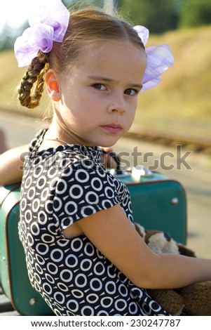 Five year old girl with suitcase waiting at the train station