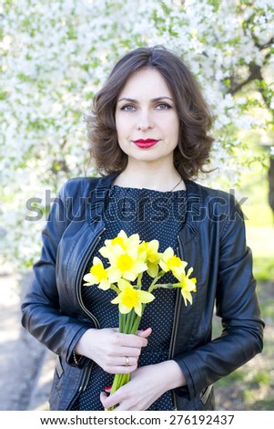 portrait of the young girl with a bouquet of narcissuses among the blossoming cherry