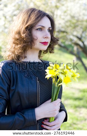 portrait of the young girl with a bouquet of narcissuses among the blossoming cherry