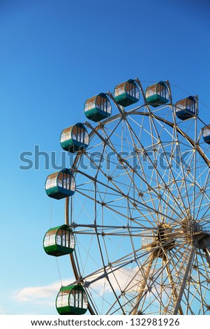 Ferris wheel turns around under the blue sky. A Ferris wheel turns around under the blue sky. It is a colorful Ferris wheel.