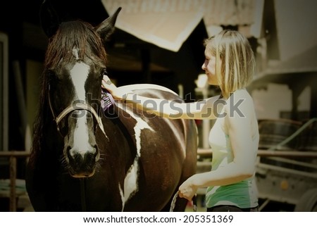 young beautiful woman cleans horse.