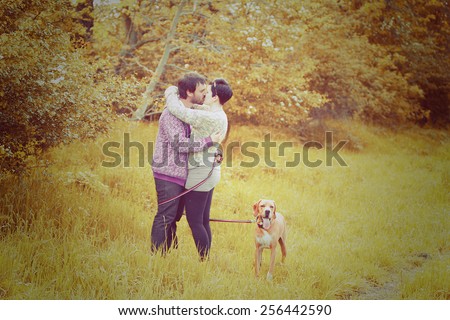 young love couple man and woman kiss on walk with dog in autumn nature