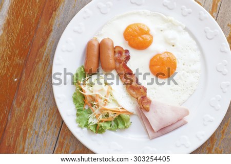 breakfast meal with ham sausage bacon egg and salad on wooden background
