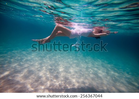 Slim beautiful girl lying on the waves on underwater background