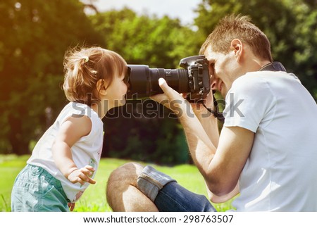 Happy father making photo of his daughter using professional camera