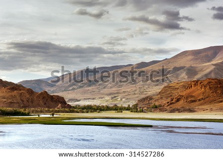 Beautiful landscape with big lake, red mountains and cloudy sky