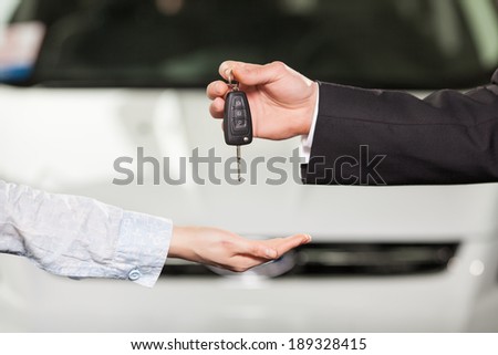 Now this car is yours. Car salesman giving the key to the new car owner
