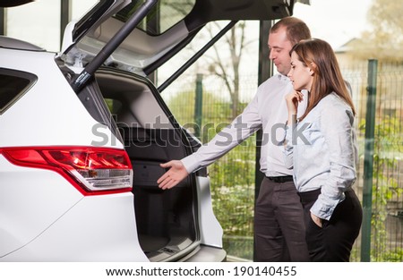 It?is so roomy inside. Handsome young car salesman showing the car trunk to the customer