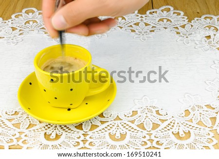 human hand  and  silver spoon stirs coffee