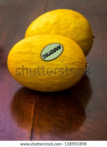 Studio shot of two melons on an old wooden table. One melon has a 