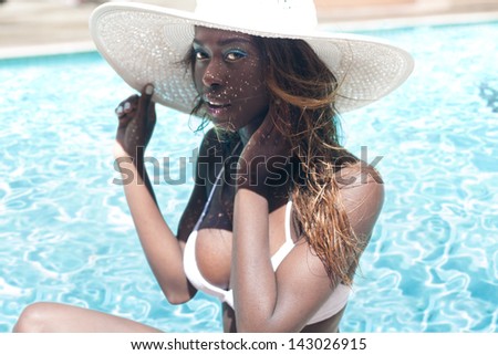 Portrait of African American young woman wearing a hat on the side of swimming pool