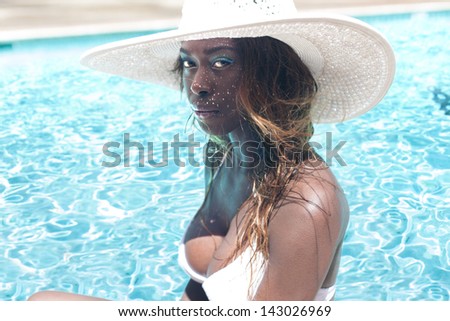 Portrait of African American young woman wearing a hat on the side of swimming pool