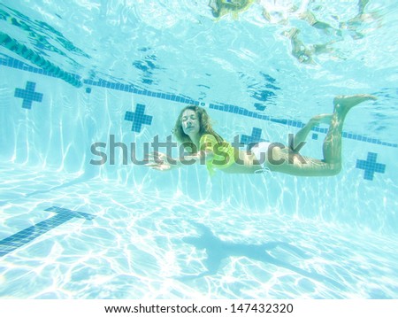 Young woman swimming underwater at swimming pool.