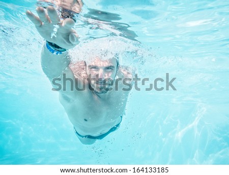 Young man swimming the front crawl in a pool, taken underwater