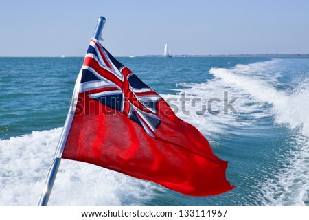 British Red Ensign flying at the back of a leisure motor boat with wash from the propellers