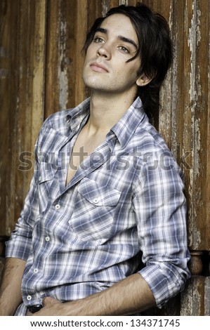 Young sexy male posing, leaning against wooden wall.