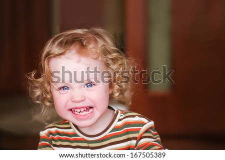 Closeup portrait of preschooler with strawberry blonde curly hairs who snarls