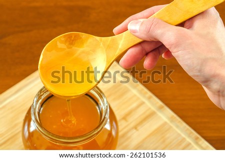 Hand holding wooden spoon with honey