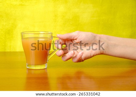 Woman\'s hand is holding peach juice in the glass