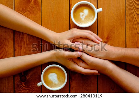 Couple in love holding hands in a cafe, top view