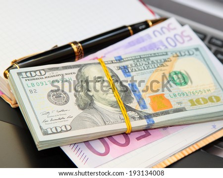 Paper money, notebook, handle Pack of banknotes against a notebook and the handle.