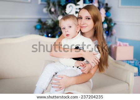 Mom sits with a boy in her arms near a Christmas tree
