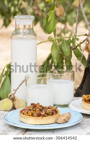 nuts, almonds  and caramel tart, with almond milk\
on a rustic background in the almond orchard
