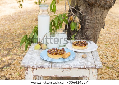 nuts, almonds  and caramel tart, with almond milk\
on a rustic background in the almond orchard