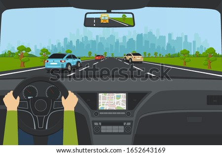 City traffic on the highway with car dashboard and panoramic view on modern city with skyscrapers and suburbs on background mountains, hills. Road with cars leading to city.