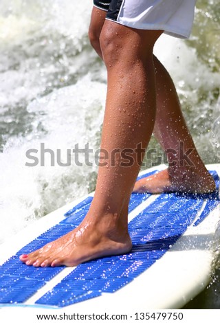 Closeup of female legs on a wake surf board