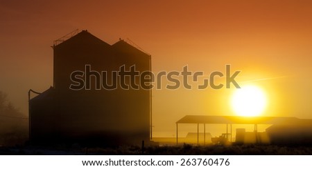 Old Farm Silos ans tractor at sunrise