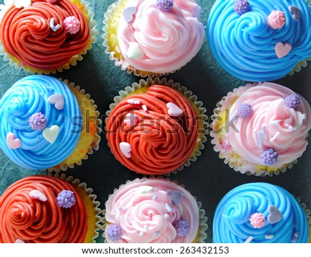 Assorted cream cupcakes including red, pink and blue
