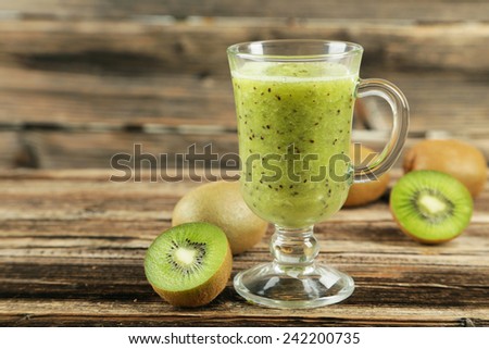 Fresh kiwi smoothie in glass on brown wooden background