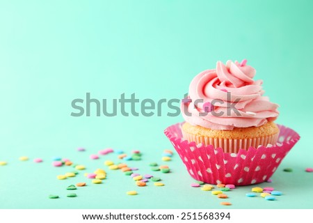 Tasty cupcake on green background