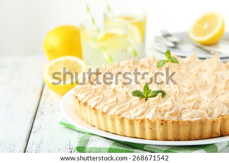 Lemon meringue pie on plate on white wooden background
