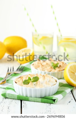 Lemon meringue pie in bowl on white wooden background