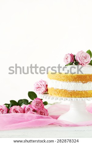 Sweet cake on cake stand on white wooden background