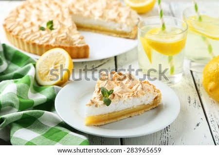 Lemon meringue pie on plate on white wooden background