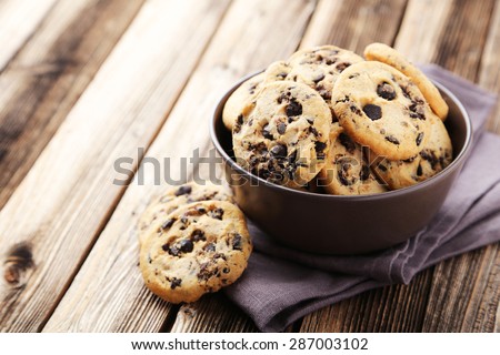 Chocolate chip cookies in bowl on brown wooden background